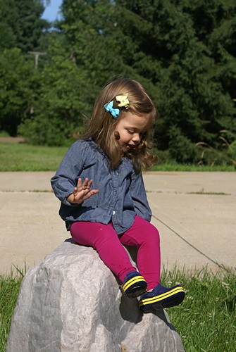 Madeline Eloise sitting on our fake rock in our front yard (it's the cover for our well).