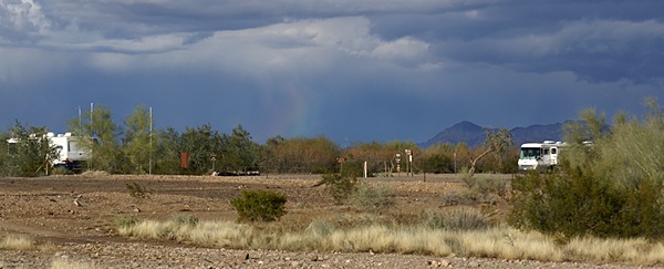 Rainbow colors refract from the rain near the center of this scene. AZ-95 looking NE over the Plomosa Rd BLM STVA.