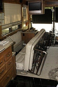 Driver side sleeper sofa unscrewed from the floor and laying on its back. Both end panels are off and the drawer and slides have been removed.