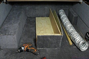 Storage compartment under the lift-up bed platform.  The two boxes concealed and protectd 4" flexible HVAC ducts.