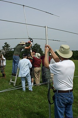 Larry (K8UT) holds the 6m beam while Steve (N8AR) and others attach the 20m beam to the mast of the taller tower.