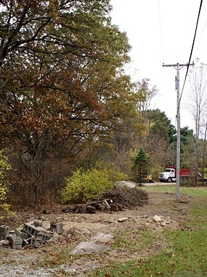 Debris piled where the new driveway extension will go. Phil’s truck and large excavator in the distance on the road at the discharge end of the culvert.